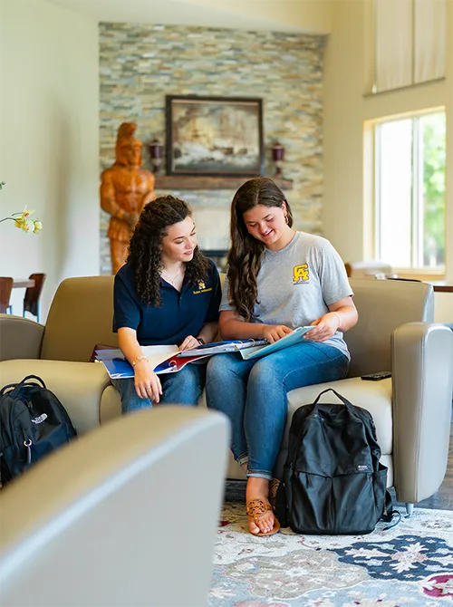 Two students on couch with books